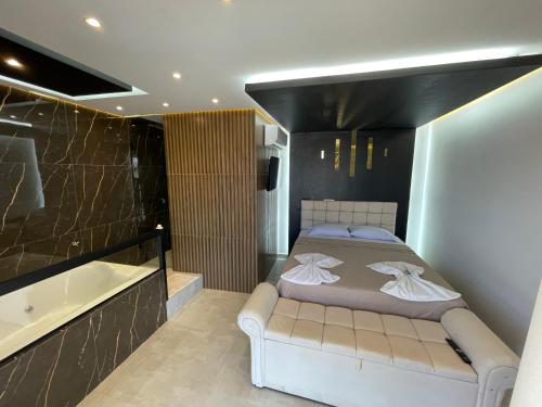 a bedroom with a bed and a bath tub at Suíte Gold com varanda e Hidro 302 in Santo Antônio do Descoberto