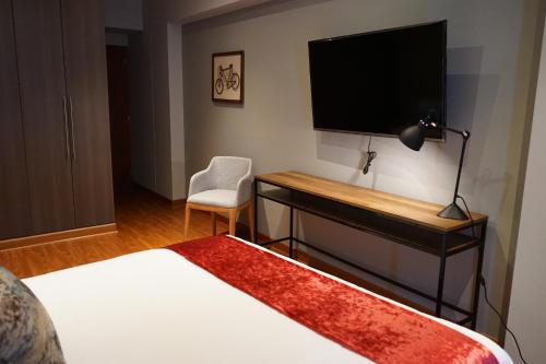 1 dormitorio con escritorio, TV y cama en Larcomar Luxury Penthouse, en Lima