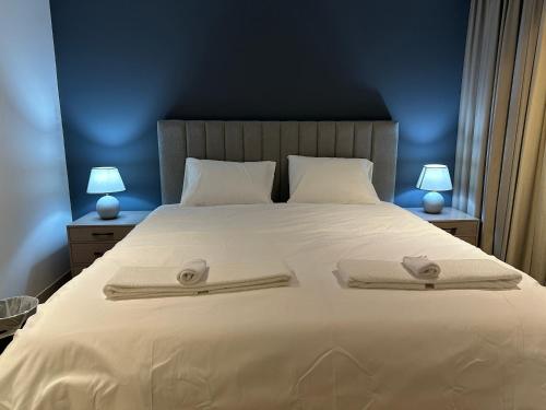 a bedroom with a large white bed with two lamps at Pinnacle Row Luxe Retreat in Muscat