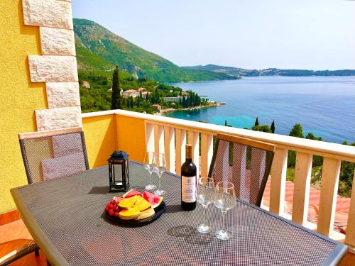 a table with a bottle of wine and glasses on a balcony at Apartments Sunset in Mlini