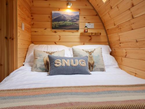 a bed in a wooden cabin with a snug sign on it at Caban Tirion in Machynlleth