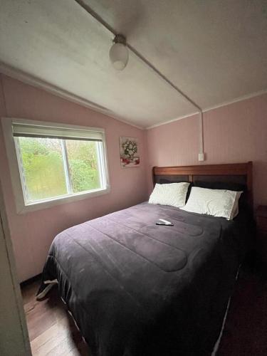 a bedroom with a large bed with a window at Cabanas y hostal tepual puerto montt in Puerto Montt
