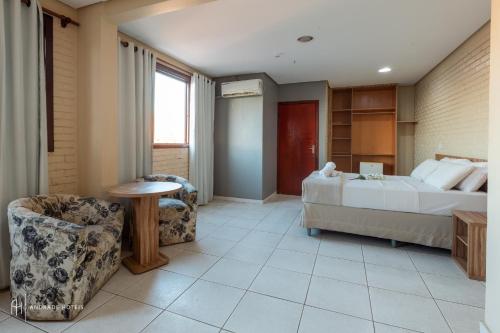 a bedroom with a bed and a table and a chair at Rede Andrade Goiania Centro in Goiânia