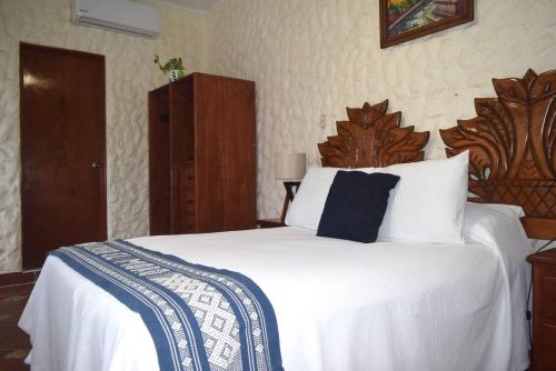a bedroom with a large white bed with a wooden headboard at Hotel Casa el Moro in Puerto Morelos