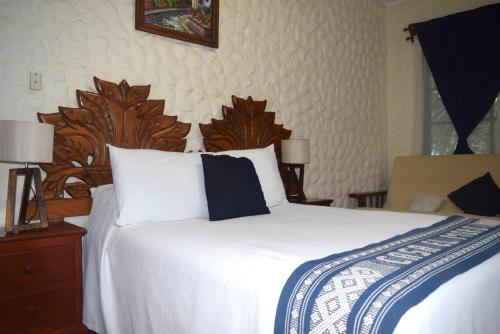a bedroom with a large white bed with a wooden headboard at Hotel Casa el Moro in Puerto Morelos