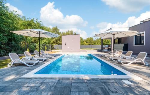 a swimming pool with lounge chairs and umbrellas at Amazing Apartment In Nedescina in Nedeščina