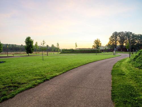 a winding road in a park with green grass at Forest Mansion Retreat in Antoing