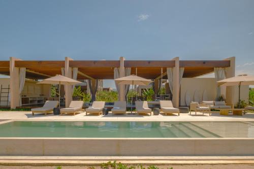 a swimming pool with lounge chairs and umbrellas at ONTO House Puerto Escondido in Tlachicón