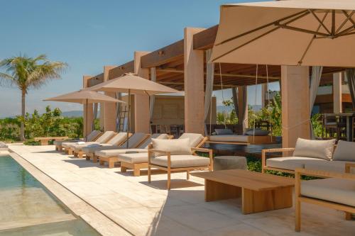 a resort with a pool and chairs and umbrellas at ONTO House Puerto Escondido in Tlachicón