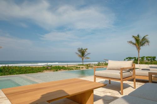 a patio with a table and a chair and the ocean at ONTO House Puerto Escondido in Tlachicón