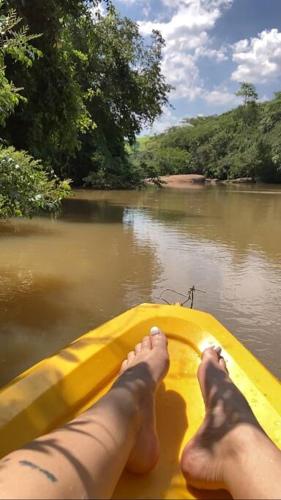 a person with their feet on a yellow boat on a river at Recanto das Aguás in Cosmópolis