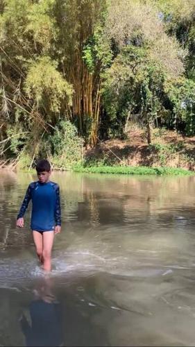 a woman standing in the water in a river at Recanto das Aguás in Cosmópolis
