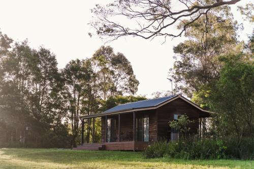 a small house with a blue roof in a field at Cabins at LaPera Estate Lovedale Wedding Chapel in Lovedale