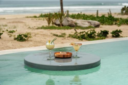 a table with two drinks on a swimming pool at ONTO House Puerto Escondido in Tlachicón