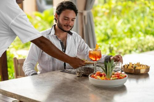 a man sitting at a table with a plate of food at ONTO House Puerto Escondido in Tlachicón