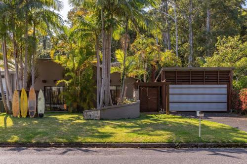 a house with a garage and palm trees at Bali by the Bay - Tarbuck Bay in Smiths Lake