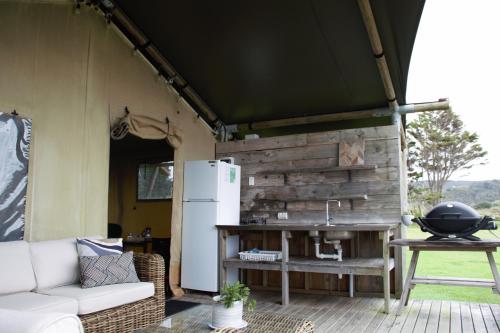 a living area of a tent with a refrigerator and a table at Pakiri Beach Holiday Park in Pakiri