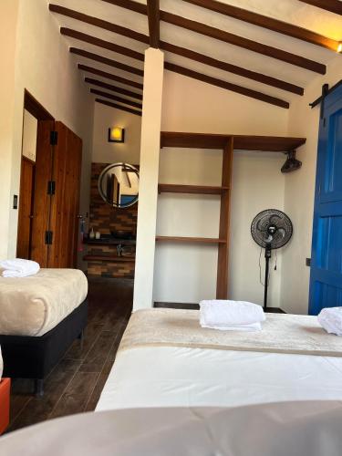 a bedroom with two beds and a fan at Casa Iris Hotel Boutique in Barichara