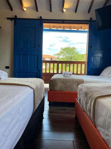 two beds in a room with a view of a balcony at Casa Iris Hotel Boutique in Barichara