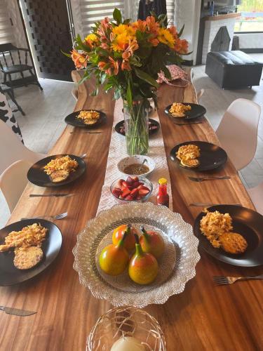 a wooden table with plates of food and a vase of flowers at Luxury Finca el Ensueño, casa entera, con Sauna, Jacuzzi, BBQ y Caballos in Tenjo