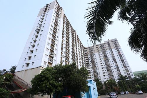 a tall white building with cars parked in front of it at Nusantara Rooms Mutiara By Reccoma in Bekasi
