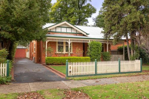 a red brick house with a white picket fence at White Rabbit on Jones- central sophistication in Albury