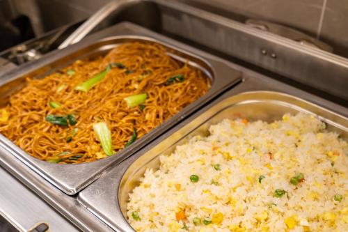 two metal trays of food with rice and noodles at Rezen Select Shanghai International Resort in Shanghai