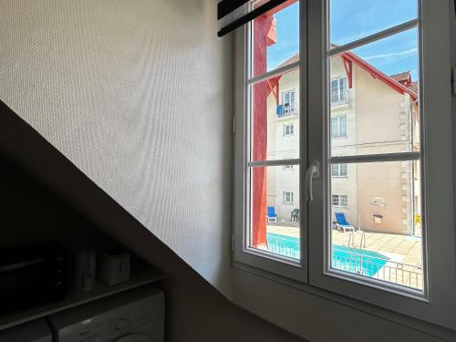 - une fenêtre dans une chambre avec vue sur la piscine dans l'établissement Studio à 200m des thermes avec piscine, parking et WiFi - FR-1-541-112, à La Roche-Posay