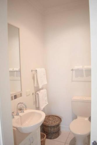 a white bathroom with a sink and a toilet at Sophisticated Elegance at the Gardens in Albury