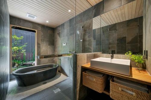 La salle de bains est pourvue d'une baignoire noire et d'un lavabo. dans l'établissement Izuki Machiya House, à Nishi-kujō-Toriiguchichō