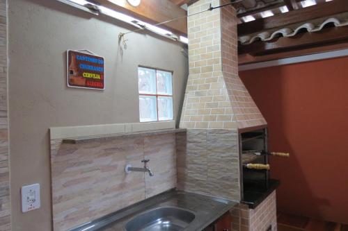 a kitchen with a sink and a brick oven at Casa da Fran in Maresias