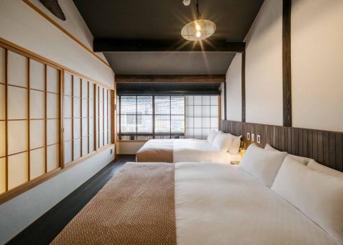 deux lits dans une chambre avec deux fenêtres dans l'établissement Izuki Machiya House, à Nishi-kujō-Toriiguchichō