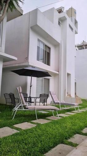 a group of chairs and an umbrella in front of a building at La ideal Alberca climatizada in Tlayacapan