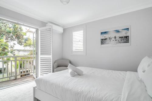 a white bedroom with a bed and a chair at The Newtowner - In the Heart of Newtown! in Sydney