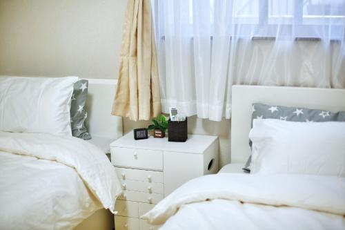 a white bedroom with two beds and a window at アキラ商事 in Tokyo