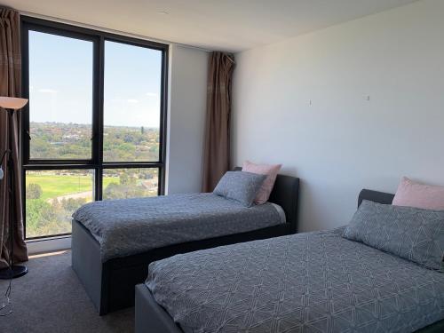 a bedroom with two beds and a large window at Panoramic views in luxurious brand new apartment in Sydney