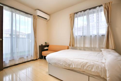 a bedroom with a bed and a chair and windows at アキラ商事 in Tokyo