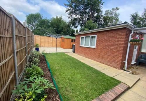 a backyard with a brick fence and grass at Hawtհorn Guestհouse in Cambridge