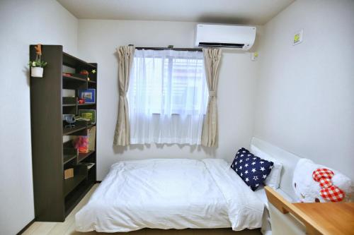 a bedroom with a white bed and a window at アキラ商事 in Tokyo