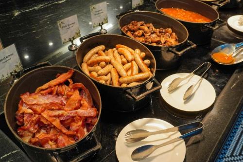 a buffet with four pots of food on a table at Pullman Singapore Orchard in Singapore