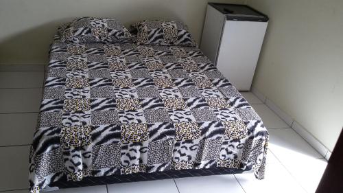 a bed with a leopard print blanket on it at Hotel Pousada Praia e Sol in Bertioga