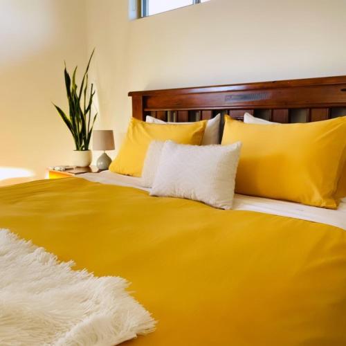 a large yellow bed with yellow pillows on it at Serenity in Style in Kalbarri