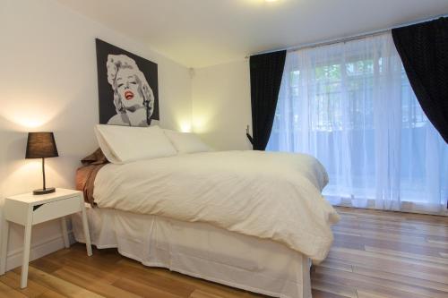 a bedroom with a white bed and a large window at Le 2662 Charlemagne in Montreal