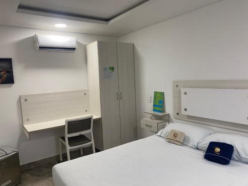 a bedroom with a white bed and a desk at Hotel deluxe oasis de la colina boutique in Girardot