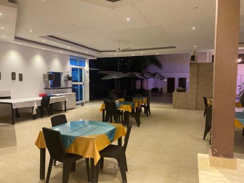a dining room with tables and chairs and a kitchen at Hotel deluxe oasis de la colina boutique in Girardot
