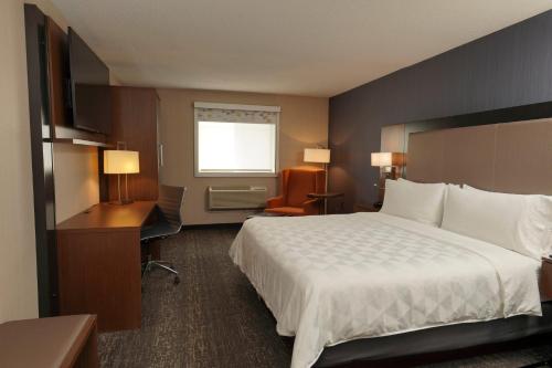 a hotel room with a large bed and a desk at Holiday Inn & Suites Chicago-Carol Stream Wheaton by IHG in Carol Stream