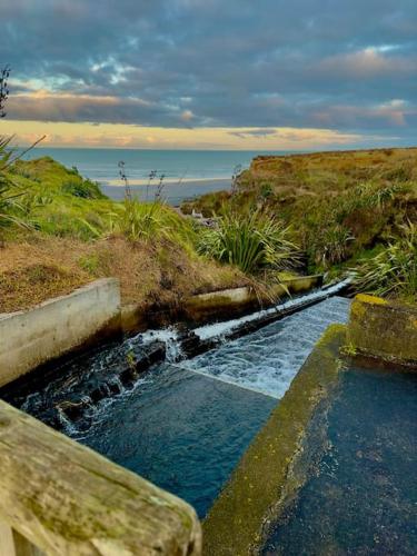 a stream of water with a bench and the ocean at Luxury Absolute Ocean View Lodge in Waverley