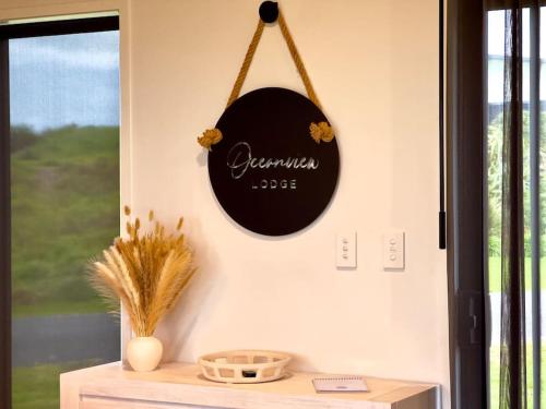 a black clock hanging on a wall next to a window at Luxury Absolute Ocean View Lodge in Waverley