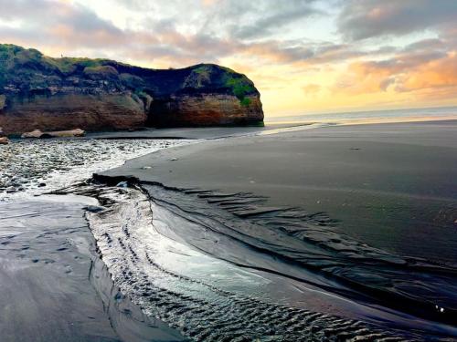 a view of a beach at sunset with a cliff at Luxury Absolute Ocean View Lodge in Waverley