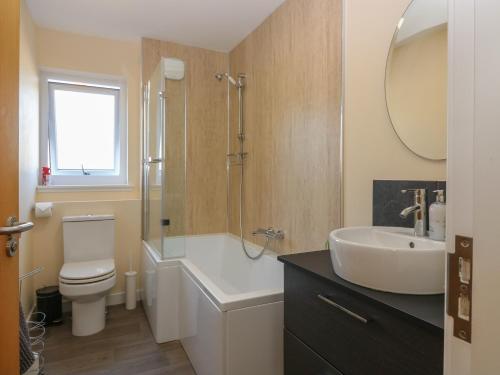 un bagno con lavandino, WC e specchio di Berg Cottage a Ballindalloch